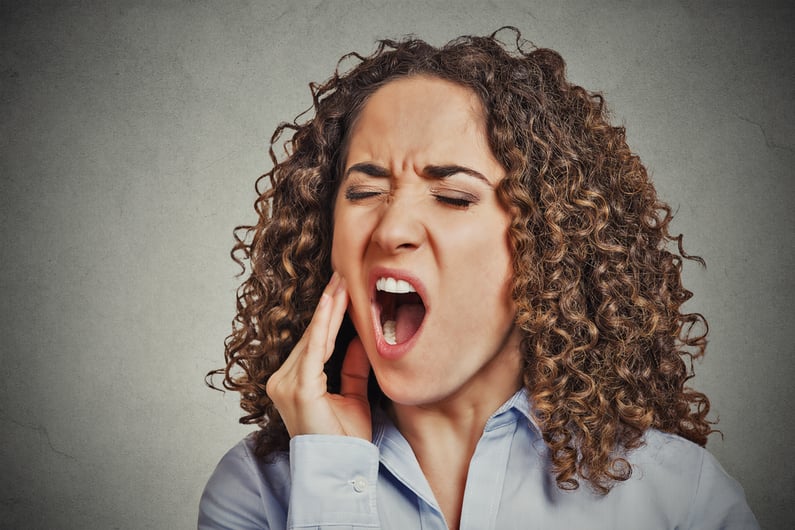 Closeup portrait young woman with sensitive tooth ache crown problem about to cry from pain touching outside mouth with hand isolated grey wall background. Negative emotion facial expression feeling-1